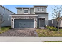 Two-story home with gray siding, stone accents, and a two-car garage at 4409 Lions Gate Ave, Clermont, FL 34711