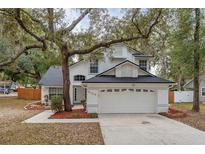 Two-story house with white exterior, black roof, and mature landscaping at 5100 Neponset Ave, Orlando, FL 32808