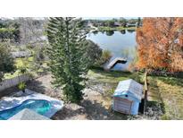 Aerial view of a private backyard with a pool, shed, and serene lake access via a wooden dock at 9511 Lake Douglas Pl, Orlando, FL 32817