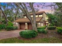 Charming two-story home features a brick facade, tile roof, and lush landscaping in a serene setting at 136 Woodmill Rd, Longwood, FL 32779