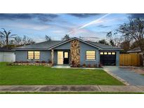 Newly renovated home with gray exterior, stone accents, and a modern garage door at 272 Iowa Woods W Cir, Orlando, FL 32824