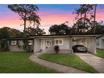 Mid-century modern home with gray exterior, landscaping, and driveway at 5102 Lake Howell Rd, Winter Park, FL 32792