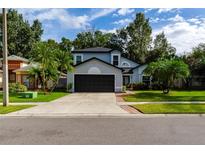 Two-story house with a gray exterior, black garage door, and landscaped yard at 749 Silver Birch Pl, Longwood, FL 32750