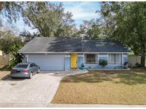 Cute blue house with yellow door, paved driveway, and landscaped yard at 7779 Murcott Cir, Orlando, FL 32835