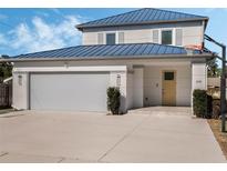 Two-story house with a blue metal roof, attached garage, and basketball hoop at 1975 Biscayne Dr, Winter Park, FL 32789