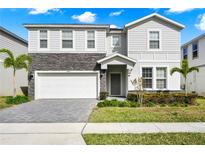 Two-story house with gray siding, stone accents, and a two-car garage at 1986 Summer Dr, Davenport, FL 33897