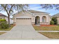 One-story house with beige exterior, two-car garage, and landscaping at 2078 Marsh Hawk Dr, Orlando, FL 32837