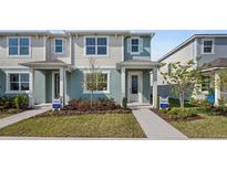 Two-story townhome with light teal and beige exterior, landscaping, and walkway at 12463 Shipwatch St, Orlando, FL 32832