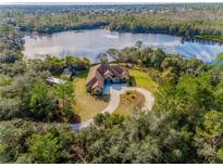 Luxury home on a lake with circular driveway, surrounded by lush greenery at 1851 Grand Keahl Ln, Deltona, FL 32738