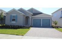 Gray house with blue doors and a paved driveway at 4476 Lions Gate Ave, Clermont, FL 34711