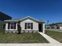 Charming single-story home featuring a stone accent wall and lush green lawn under a bright blue sky at 5505 Stable Mate Dr, Apopka, FL 32712