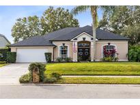 Tan one-story house with a gray roof, palm tree, and manicured lawn at 623 Yorkshire Dr, Oviedo, FL 32765