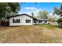 Ranch style home with white brick exterior, black windows, and a spacious lawn at 200 Florida Ave, Geneva, FL 32732