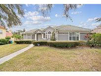 Gray house with tile roof, manicured lawn, and walkway at 2225 Kettle Dr, Orlando, FL 32835