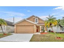 Two-story house with tan exterior, red door, and landscaped yard at 2267 Santa Lucia St, Kissimmee, FL 34743