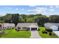 Aerial view of a single-story house with a paved driveway and landscaped yard at 26608 Racquet Cir, Leesburg, FL 34748