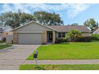 One-story house with a gray exterior, attached garage, and well-maintained lawn at 5405 Justine Way, Winter Park, FL 32792