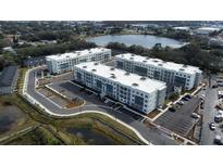 Aerial view of a modern apartment community with ample parking and a lake at 1230 Southstation Pl # 105, Orlando, FL 32809