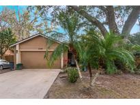 Tan house with a two-car garage and mature landscaping at 1309 Paradise Ln, Winter Park, FL 32792