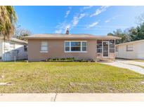 Tan single story home with landscaped lawn, walkway and screened porch at 421 Jefferson St, Daytona Beach, FL 32114