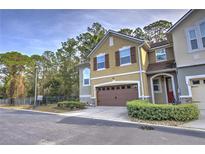 Two-story townhome with brown garage door and landscaping at 1102 Victoria Glen Dr, Sanford, FL 32773