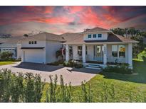 White two-story house with a brown roof, front porch, and a landscaped yard at 1406 Saxon Dr, New Smyrna Beach, FL 32169