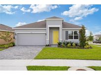 Charming single-story home with a yellow front door, manicured lawn and gray brick driveway at 1343 Foran Manor Rd, Haines City, FL 33844
