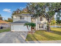 Two-story house with white exterior, a white garage door, and a palm tree in the front yard at 1727 Wood Violet Dr, Orlando, FL 32824