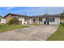 Ranch-style home with a large driveway and mature landscaping at 6517 Precourt Dr, Orlando, FL 32809