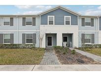 Two-story townhome with gray siding, shutters, and a brick walkway at 297 Jetty Way, Davenport, FL 33897
