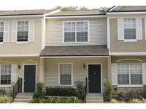 Tan townhome with dark gray door, shutters, and landscaping at 4145 Plantation Cove Dr, Orlando, FL 32810