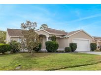 Tan house with a white garage door and well-manicured lawn at 63 York Ct, Kissimmee, FL 34758