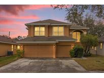 Two-story house with beige exterior, two-car garage, and landscaped yard at 8567 Baywood Vista Dr, Orlando, FL 32810