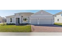 Charming single-story home showcasing a brick driveway, manicured lawn, and inviting facade at 5000 Northern Dove Ave, Mount Dora, FL 32757