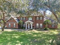 Charming two-story red brick home with a well-manicured lawn and mature trees at 9501 Hempel Cove Blvd, Windermere, FL 34786