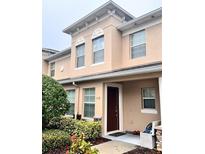 Tan two-story townhome with a brown door, landscaping, and walkway at 112 Augustus Pt, Sanford, FL 32773