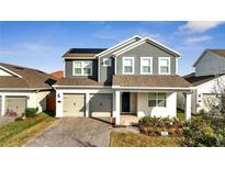 Two-story house featuring gray siding, solar panels, and a two-car garage at 14789 Milfoil Ave, Orlando, FL 32827