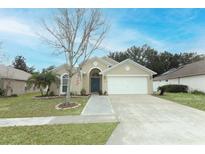 House exterior featuring a landscaped lawn, paver walkway, and two-car garage at 30129 Pga Dr, Sorrento, FL 32776