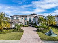 Stunning estate home with manicured lawn, lush tropical landscaping, a circular drive, and an elegant water feature at 4089 Isabella Cir, Windermere, FL 34786