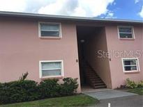 Two-story building with four windows, stairs, and landscaping at 5885 Dahlia Dr # 29/115, Orlando, FL 32807