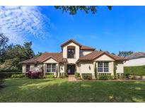 Two-story house with brown tile roof, landscaping, and a large front yard at 6874 Valhalla Way, Windermere, FL 34786