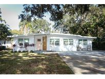 Updated mid-century modern home with a pink door and manicured lawn at 7007 Seminole Dr, Belle Isle, FL 32812