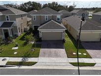 Aerial view of a two-story house with a brick driveway and a well-maintained lawn at 1726 Tree Shade Dr, Davenport, FL 33837