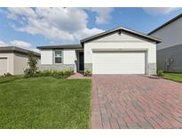 Charming single-story home with a brick driveway, well-maintained lawn, and an attached two-car garage at 2307 White Tail St, Davenport, FL 33837