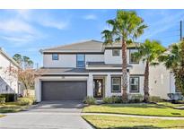 Two-story house with gray accents, a two-car garage, and palm trees at 2639 Calistoga Ave, Kissimmee, FL 34741