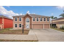 Two-story house with a three-car garage and tan exterior at 3433 Glossy Leaf Ln, Clermont, FL 34711