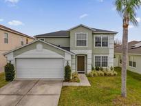 Two-story house with a green exterior, two-car garage, and landscaping at 1255 Blackwater Pond Dr, Orlando, FL 32828