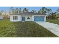 Inviting single-story home featuring a well-manicured lawn, blue accents and an attached two car garage at 1719 Sw 166Th St, Ocala, FL 34473