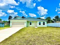 Newly constructed light green house with a two-car garage and a well-manicured lawn at 2645 Sw 155Th Ln, Ocala, FL 34473