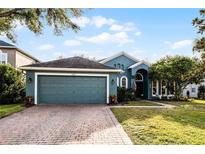 Beautiful blue house with a brick driveway, lush lawn, and mature landscaping at 3063 Juneberry Ter, Oviedo, FL 32766